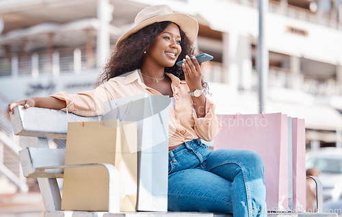 Image of Shopping, fashion and phone call, a black woman with a smile resting outside a mall. Relax on bench, happy customer after discount sale at shopping mall or designer boutique and talking on smartphone