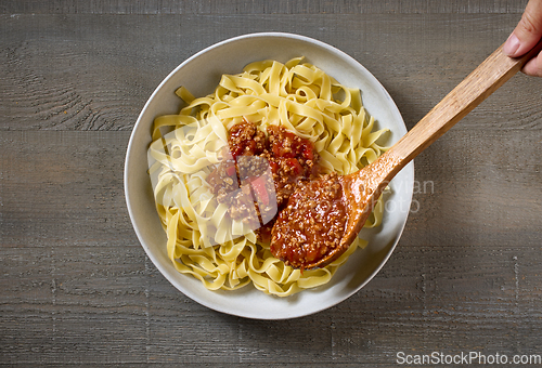 Image of bologna sauce is added to a bowl of pasta