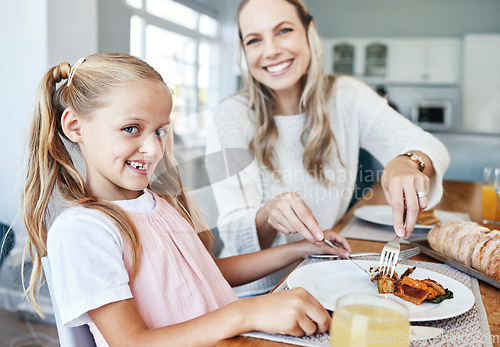 Image of Children, family and food with a girl and mother eating a meal at the dining room table at home together. Kids, lunch and love with a woman and daughter sharing a roast in celebration of an event