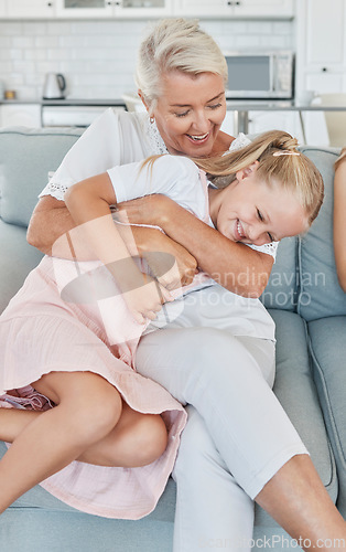 Image of Grandmother, family and child at home with a senior woman having fun, bonding and laughing for tickle and playing on living room sofa. Grandma and girl grandchild spending time in Australia house