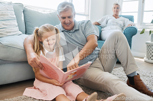 Image of Book, child and grandfather reading a story for education, knowledge and happiness together on the living room floor of their house. Elderly man helping a girl learn to read in the lounge of home