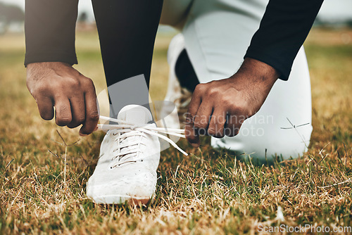 Image of Baseball, sports and shoes with a man athlete tying his laces on a grass pitch or field for training or a game. Fitness, exercise and footwear with a male player making sure his shoelaces are tied