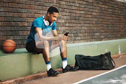 Image of Man, basketball and phone with sports app, communication and social media online outdoor. Sport male in rest after fitness, exercise and game time check, message or text on mobile 5g smartphone