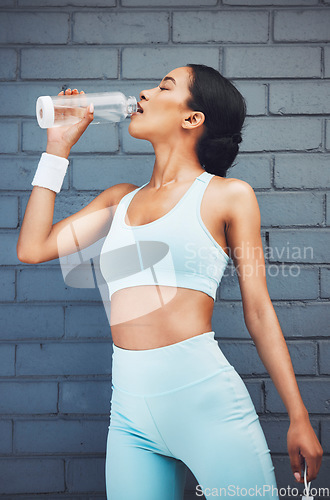 Image of Fitness, woman and drinking water for sports hydration after workout, exercise and training against wall background. Active female in healthy rehydration for physical activity, wellness and diet plan