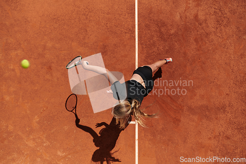 Image of Top view of a professional female tennis player serves the tennis ball on the court with precision and power