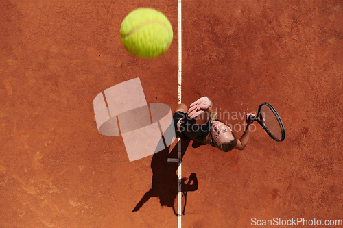 Image of Top view of a professional female tennis player serves the tennis ball on the court with precision and power