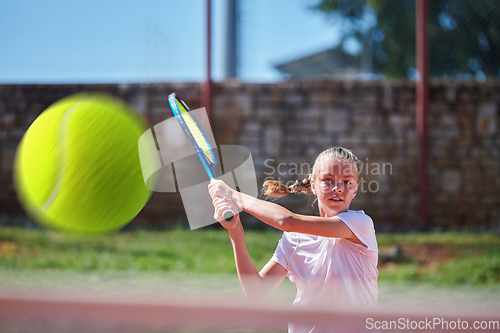 Image of A young girl showing professional tennis skills in a competitive match on a sunny day, surrounded by the modern aesthetics of a tennis court.