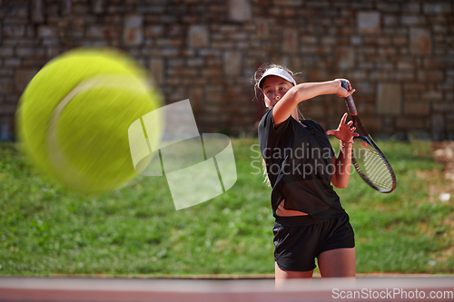 Image of A professional female tennis player serves the tennis ball on the court with precision and power