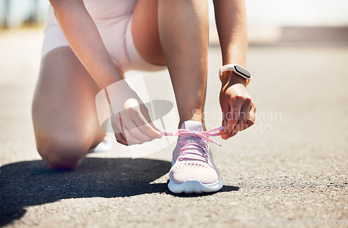 Image of Fitness, exercise and shoes with a sports woman tying her laces while running on an asphalt road or street. Workout, training and cardio with a female athlete getting ready for a run routine