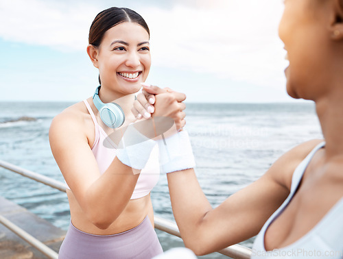 Image of Handshake, beach and happy fitness friends excited with training targets, exercise and workout goals outdoors. Smile, happiness and healthy women with girl power shaking hands with pride and joy