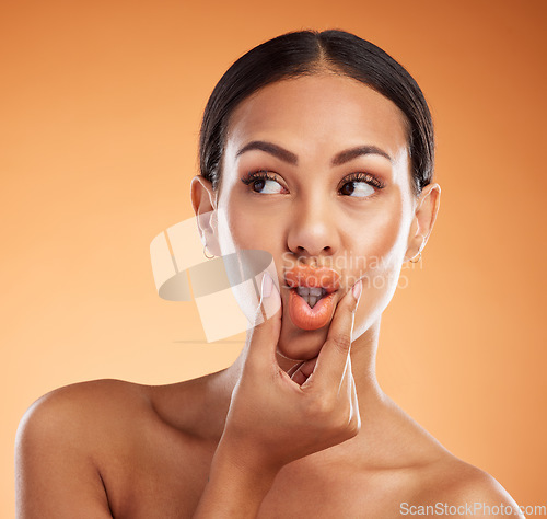 Image of Beauty, makeup and cosmetics with woman using hands to pout lips with makeup for cosmetology advertising against orange background. Face of female model showing tint, mouth and colour for skincare