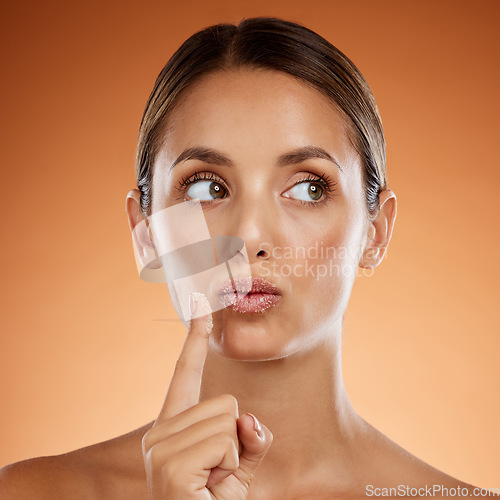 Image of Woman with sugar scrub on lips, skincare with natural product or handmade wellness treatment in studio. Girl thinking on orange background, exfoliate mouth with peeling smooth skin for beauty idea