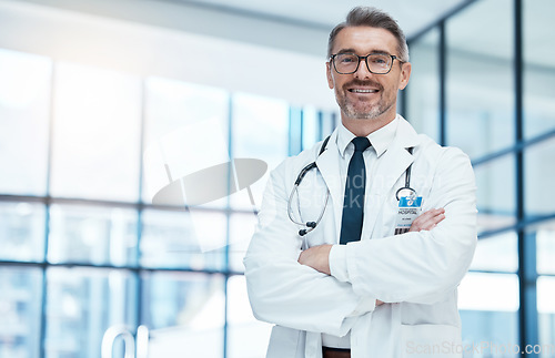 Image of Doctor, man and happy with arms crossed in hospital for medical, career and happiness for portrait. Medic, smile and work in clinic for healthcare, wellness and health while working in Washington DC