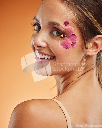 Image of Beauty, makeup and creative with woman petals on face for design, flowers and natural cosmetics against orange background in studio. Spring, skincare and smile with girl for color, model and orchid