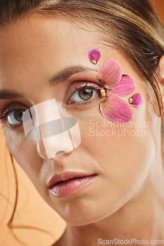 Image of Woman, flower and beauty eye makeup in portrait for cosmetics, skincare and facial wellness mockup in studio against orange background. Model, cosmetic art and orchid petals design for spring