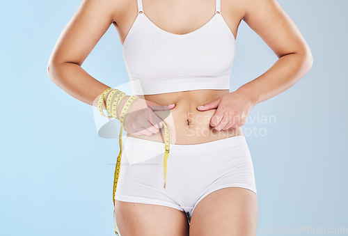 Image of Obesity, fat woman and tape measure stomach, health diet and plus size overweight on studio blue background. Abdomen cellulite, tummy tuck and liposuction surgery of chubby, obese and model body skin