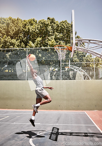 Image of Basketball, sports and jump with man on court playing games for fitness, training and health. Energy, exercise and workout with basketball player in outdoor for wellness, summer and athlete lifestyle