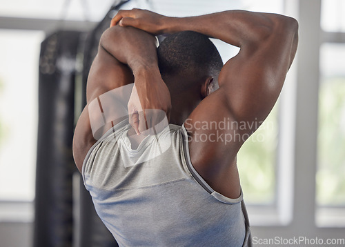 Image of Fitness, bodybuilder and black man stretching at gym for training, exercise and workout for strong powerful muscles. Back view, sports and healthy athlete starting biceps, triceps and elbow warm up