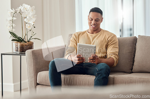 Image of Man, tablet and social media on sofa in home, internet surfing or web browsing. Happy, relax and male from India on digital tech, mobile app or streaming content, movie or online video in house alone
