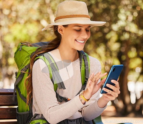 Image of Hiking, phone and woman checking gps or online map in a forest, happy, relax and navigation. Nature, adventure and smiling woman exploring the woods, sitting to text and read message on smartphone