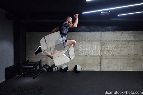 Image of A muscular man captured in air as he jumps in a modern gym, showcasing his athleticism, power, and determination through a highintensity fitness routine