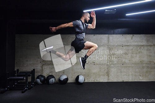 Image of A muscular man captured in air as he jumps in a modern gym, showcasing his athleticism, power, and determination through a highintensity fitness routine