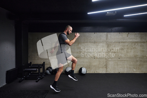 Image of A muscular man captured in air as he jumps in a modern gym, showcasing his athleticism, power, and determination through a highintensity fitness routine