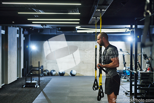 Image of A muscular man in the gym, preparing for his workout, exudes determination and focus as he gets ready to push his limits and achieve his fitness goals.