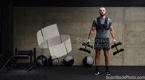 Image of A muscular man performs shoulder exercises in a modern gym, showcasing his strength and dedication to fitness.