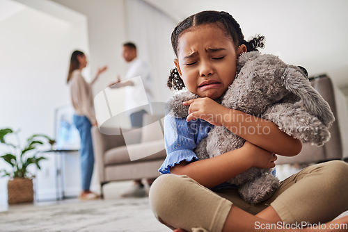 Image of Sad, little girl and crying from parent fight, argument or divorce hugging teddy at home. Unhappy young child in depression, stress and anxiety from mother and father fighting in family disagreement