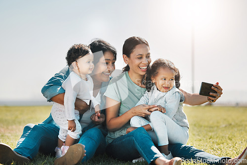 Image of Phone, selfie and family with a woman, girl and sister taking a photograph while enjoying a summer picnic on a field of grass. Love, grandmother and generations with a mother posing for a picture