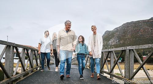 Image of Family, walking and travel with a girl and grandparents holding hands on a pier while on holiday or vacation together. Love, trust and children with a man, woman and granddaughter boding on a walk