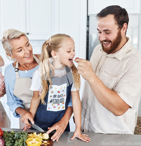 Image of Family, tomato and feeding with a girl and father eating a vegetable in the kitchen of their home together. Food, love and health with a man giving his daughter a healthy snack while cooking inside