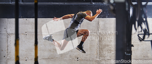 Image of A muscular man captured in air as he jumps in a modern gym, showcasing his athleticism, power, and determination through a highintensity fitness routine