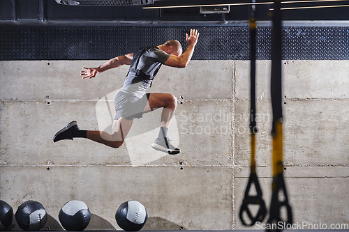 Image of A muscular man captured in air as he jumps in a modern gym, showcasing his athleticism, power, and determination through a highintensity fitness routine