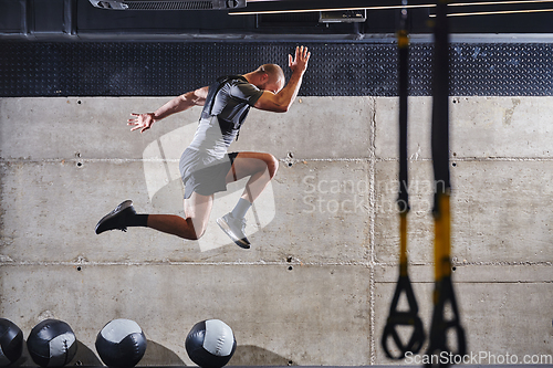 Image of A muscular man captured in air as he jumps in a modern gym, showcasing his athleticism, power, and determination through a highintensity fitness routine