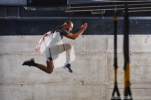 Image of A muscular man captured in air as he jumps in a modern gym, showcasing his athleticism, power, and determination through a highintensity fitness routine