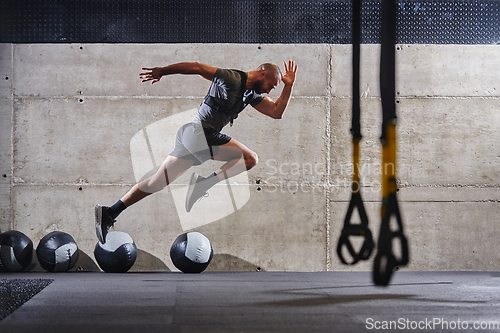 Image of A muscular man captured in air as he jumps in a modern gym, showcasing his athleticism, power, and determination through a highintensity fitness routine