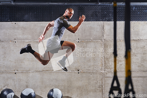 Image of A muscular man captured in air as he jumps in a modern gym, showcasing his athleticism, power, and determination through a highintensity fitness routine