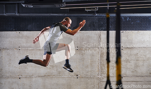 Image of A muscular man captured in air as he jumps in a modern gym, showcasing his athleticism, power, and determination through a highintensity fitness routine