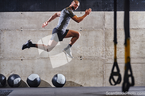 Image of A muscular man captured in air as he jumps in a modern gym, showcasing his athleticism, power, and determination through a highintensity fitness routine