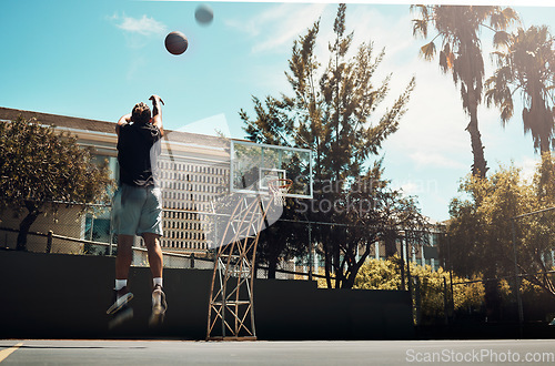 Image of Basketball, outdoor and a man shooting ball alone on basketball court in Miami summer sun. Fitness, training and health, basketball player jumping to score on court at weekend sports game practice.