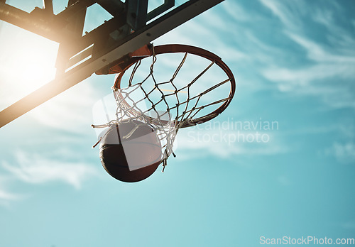 Image of Below, basketball and net with sky in summer for shooting, scoring and points to win game. Hoop, rim and ball in closeup at basketball court for sports, competition or workout at playground, outdoor