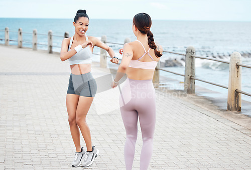 Image of Fitness, friends and women doing cardio on beach promenade before running in California. Sport, exercise and friendship motivation, girls warm up for boardwalk run with stretching, strength and sweat