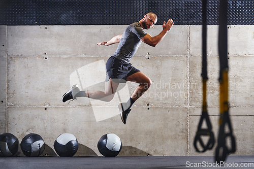 Image of A muscular man captured in air as he jumps in a modern gym, showcasing his athleticism, power, and determination through a highintensity fitness routine