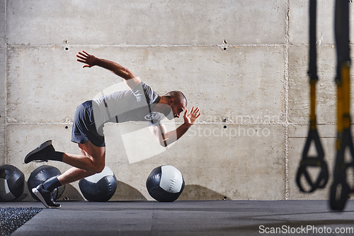 Image of A muscular man captured in air as he jumps in a modern gym, showcasing his athleticism, power, and determination through a highintensity fitness routine