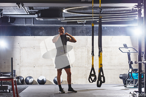 Image of A muscular man in the gym, preparing for his workout, exudes determination and focus as he gets ready to push his limits and achieve his fitness goals.