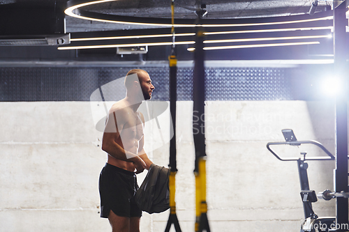 Image of A muscular man in the gym, preparing for his workout, exudes determination and focus as he gets ready to push his limits and achieve his fitness goals.