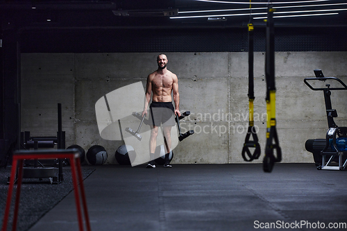 Image of A muscular man performs shoulder exercises in a modern gym, showcasing his strength and dedication to fitness.