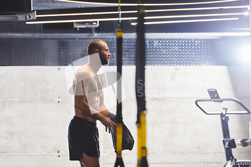 Image of A muscular man in the gym, preparing for his workout, exudes determination and focus as he gets ready to push his limits and achieve his fitness goals.